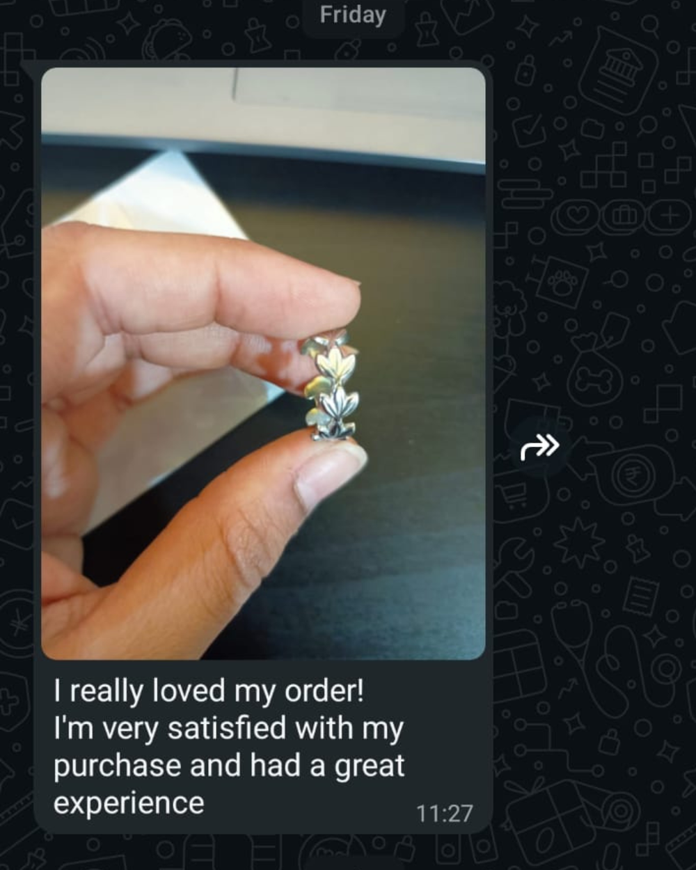 A hand holding a small silver ring with a floral or leaf-like design, shown within a messaging-style screenshot. The message text below says, 'I really loved my order! I'm very satisfied with my purchase and had a great experience.