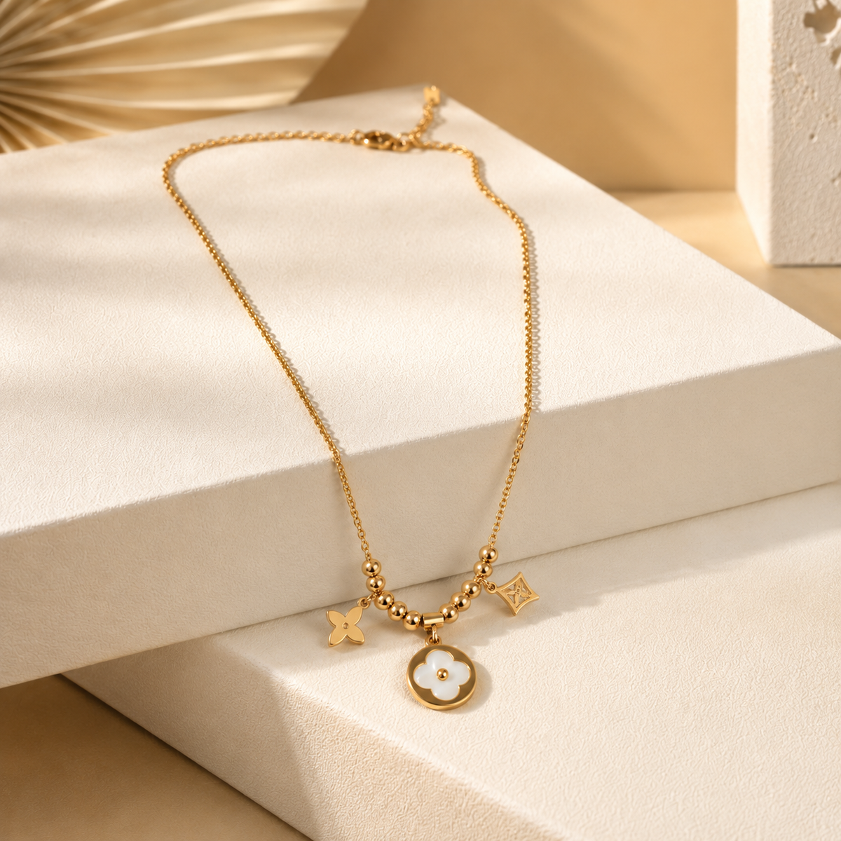 Anti tarnish gold tonned finish necklace with star and circular pendants on a beige surface