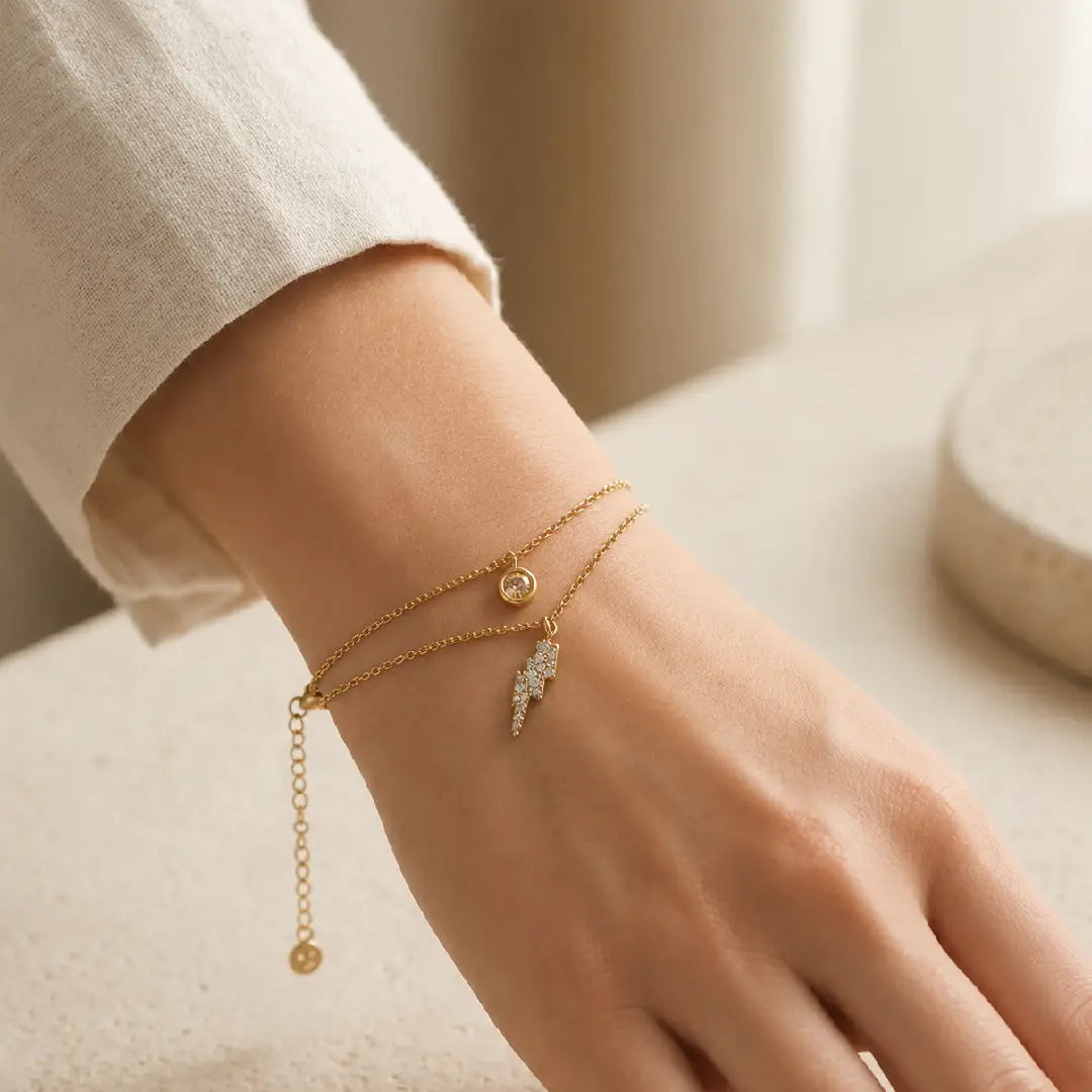 Close-up of a wrist wearing gold tonned aura dual layer bracelets with a neutral background