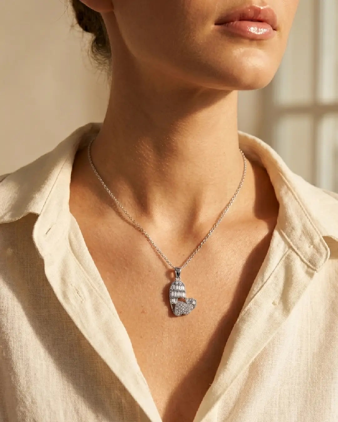 Necklace with a pendant worn by a pwomen in a light-colored shirt.
