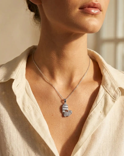 Necklace with a pendant worn by a pwomen in a light-colored shirt.