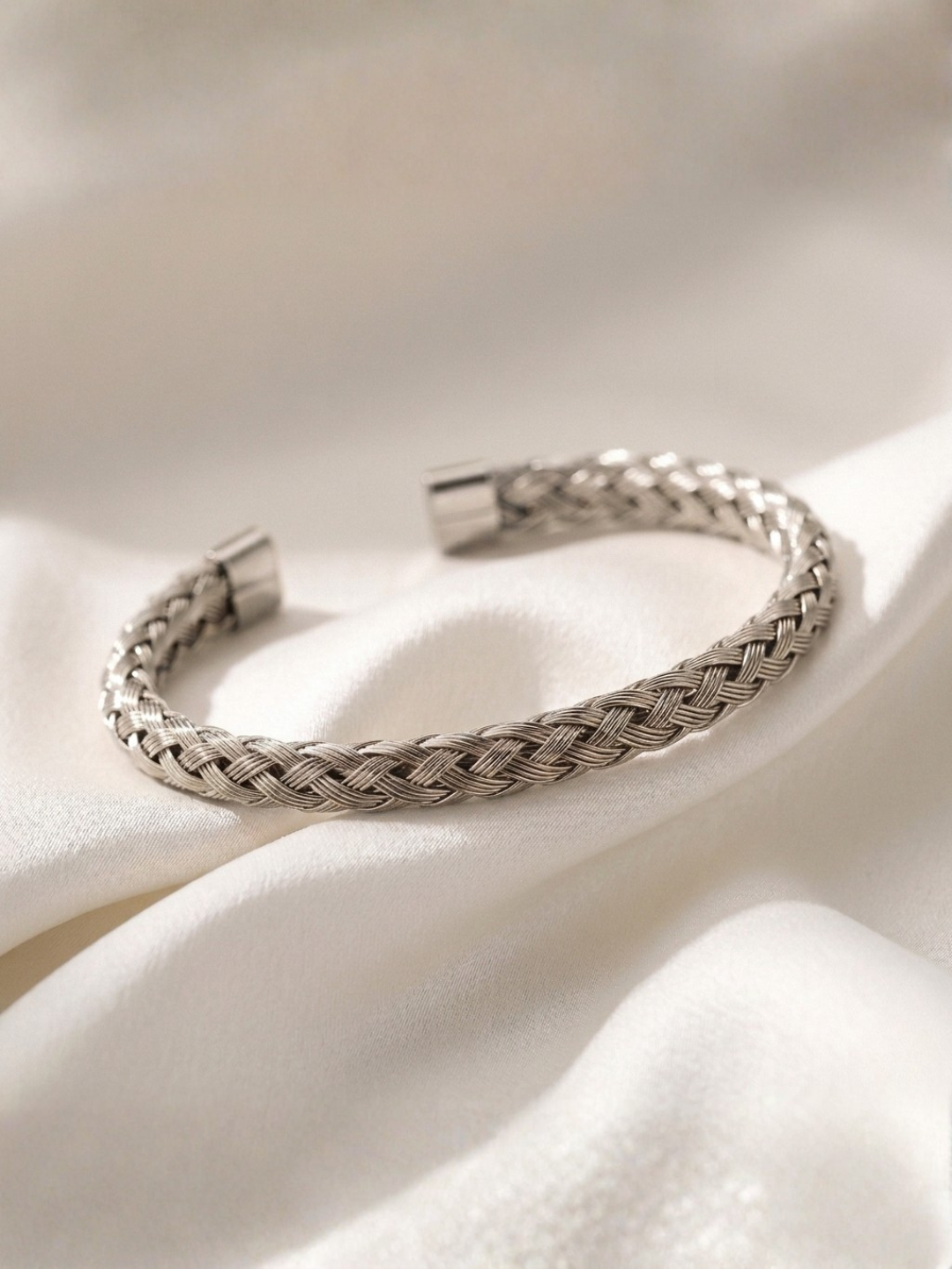 Silver braided bracelet on a white fabric background