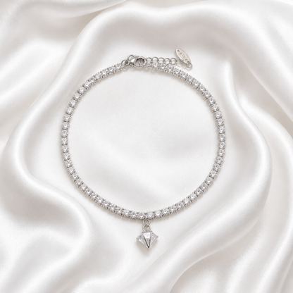 A silver-toned tennis-style choker bracelet adorned with clear cubic zirconia stones and a dangling faceted clear gemstone pendant, displayed on draped white satin fabric.