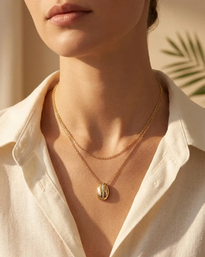 Close-up of a women wearing a gold tonned finish necklace with a beige background